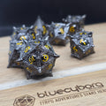 Dragon Eye Black Gold metal dice set with raised dragon eye detailing, dark gunmetal finish and gold numbers