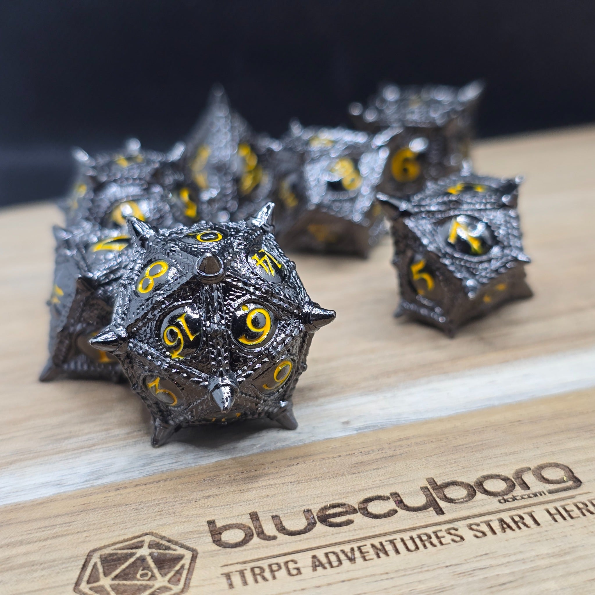 Dragon Eye Black Gold metal dice set with raised dragon eye detailing, dark gunmetal finish and gold numbers