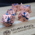 Rose Wyrm rose gold metal dice set with blue dragon detailing