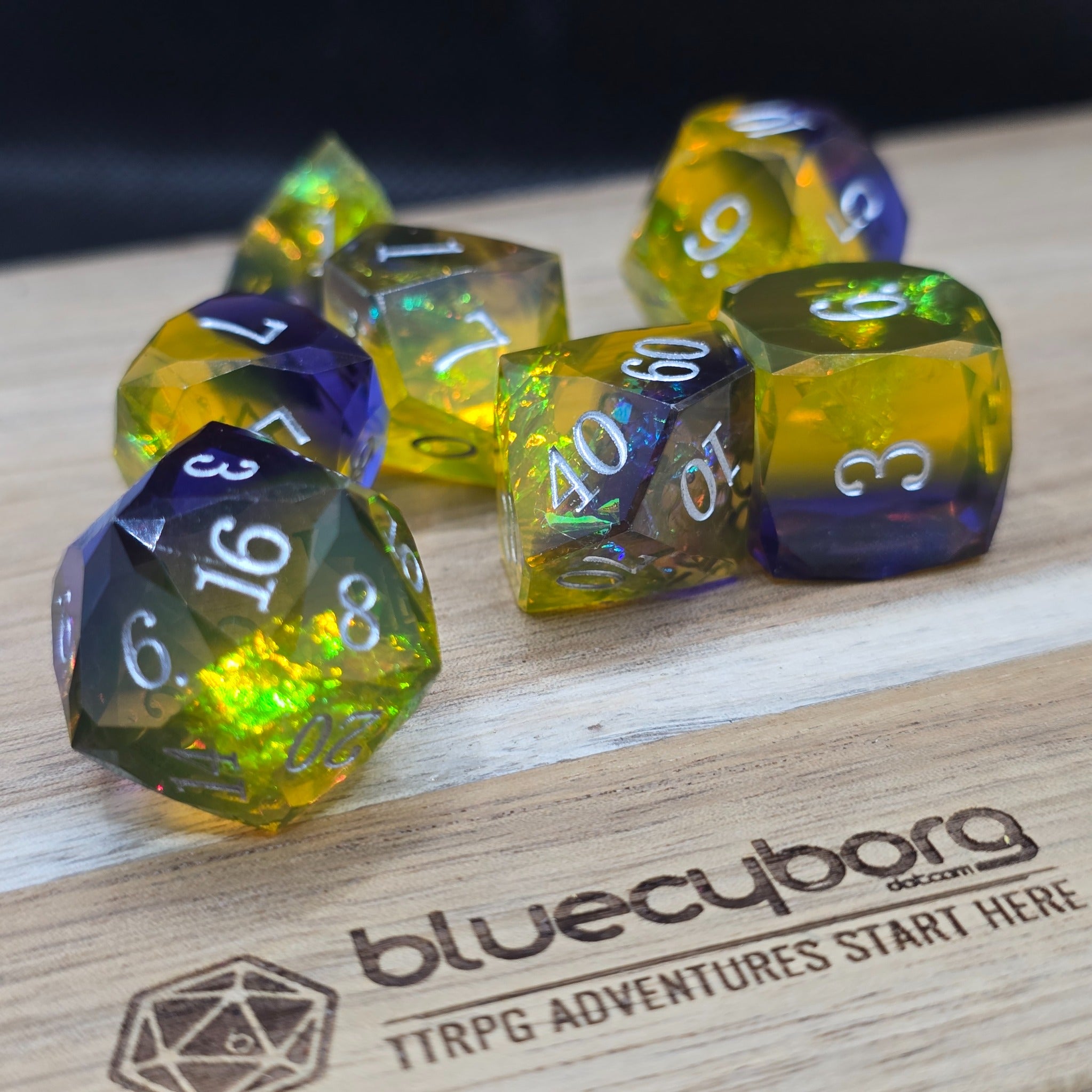 Stormlit Sapphire Jeweller’s Cut resin dice set with blue resin, yellow glow, silver numbers and faceted finish